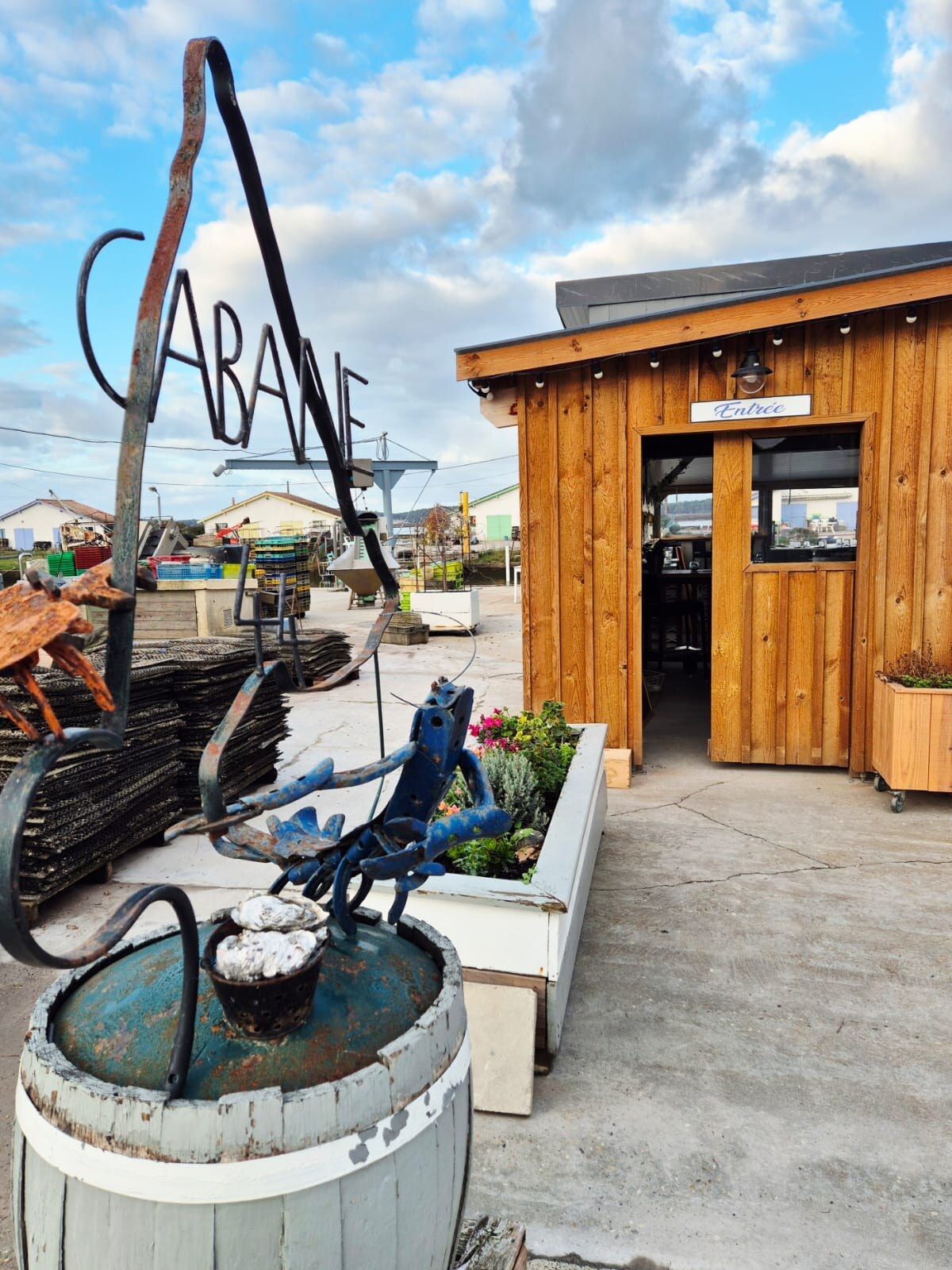 Entrée de la Cabane 44 sur le port ostréicole d'Arès : enseigne « Cabane » et façade en bois